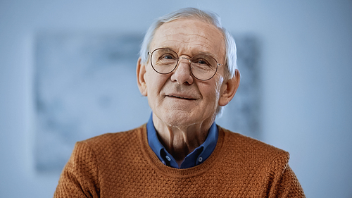 portrait of cheerful senior man in glasses on grey background