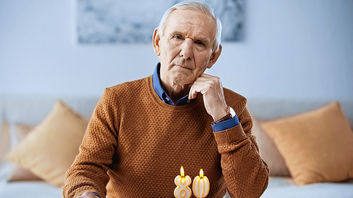 lonely elderly man celebrating birthday in front of burning candles in living room