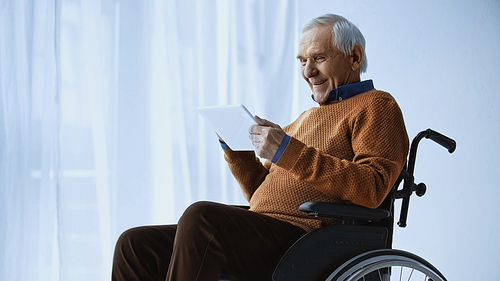 smiling elderly man in . looking at tablet in hands at retirement home