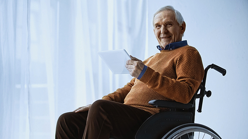 cheerful pensioner in . holding tablet in hand at retirement home