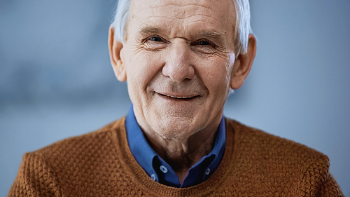 portrait of smiling elderly man on grey background