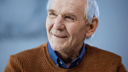portrait of cheerful elderly man looking away on grey background
