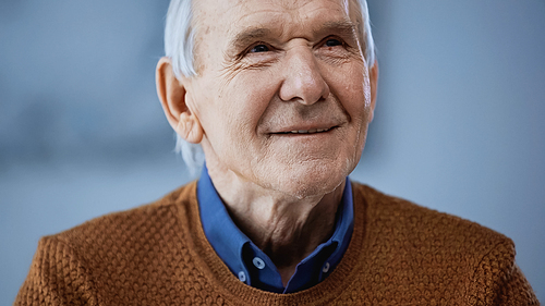portrait of positive elderly man looking away on grey background