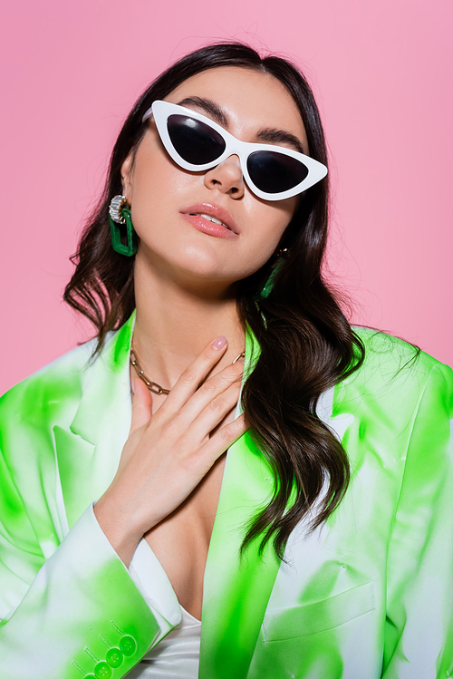 Brunette woman in sunglasses posing isolated on pink