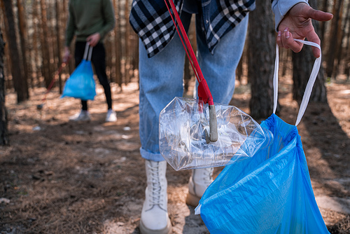 cropped view of volunteer picking up rubbish in forest