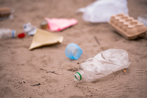 plastic bottle near blurred trash on sand