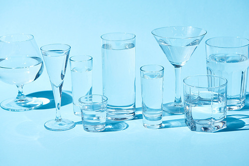 transparent glasses with clear water on blue background