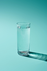 transparent glass with water on turquoise background