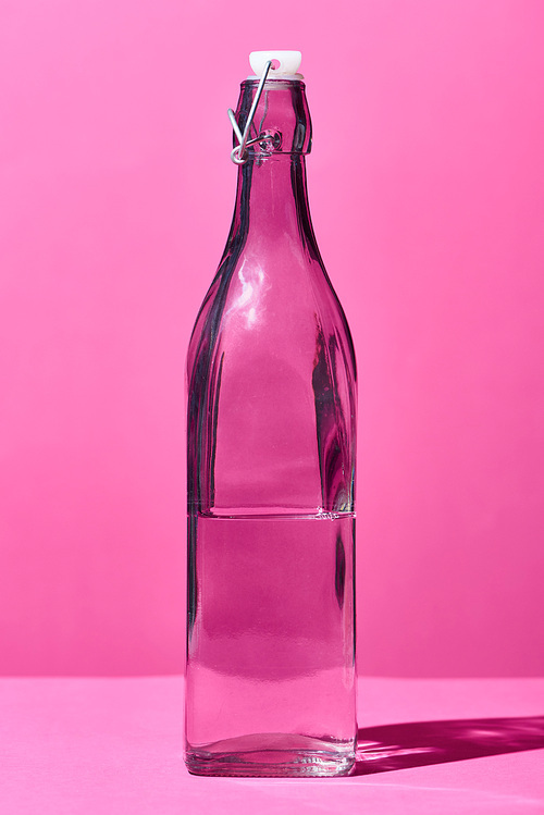 transparent bottle with water on pink background