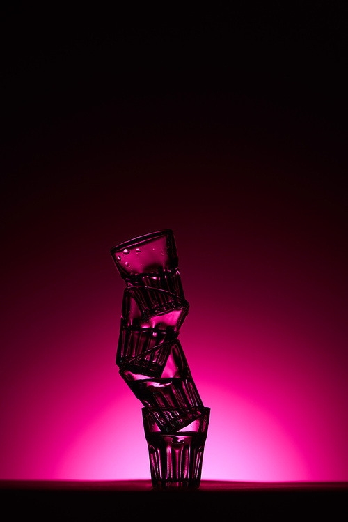 transparent glasses on dark background with pink illumination