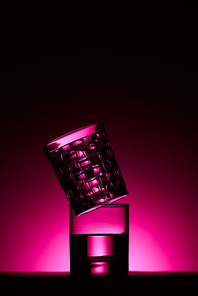 transparent glasses with water on dark background with pink illumination