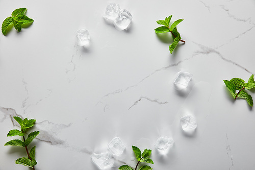 top view of green fresh mint and ice cubes on marble surface