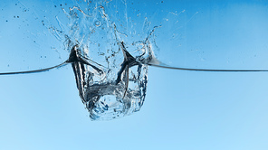 clear water with falling ice cubes and splash on blue background