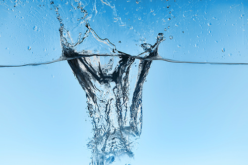 clear water with falling ice cubes and splash on blue background