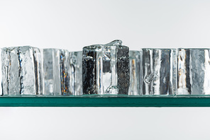 selective focus of transparent clear square ice cubes in line isolated on white