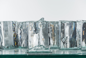 selective focus of melting transparent clear square ice cubes isolated on white