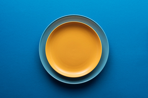 top view of blue plate under yellow one on blue background