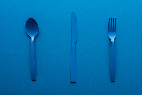 blue plastic spoon, knife and fork on blue background