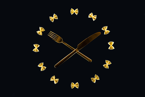 top view of clock concept with farfalle pasta, crossed fork and knife in middle isolated on black