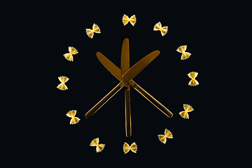 top view of farfalle pasta in circle with three crossed knives in middle isolated on black