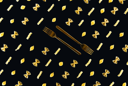 flat lay of different kinds of pasta with two metal forks in middle isolated on black