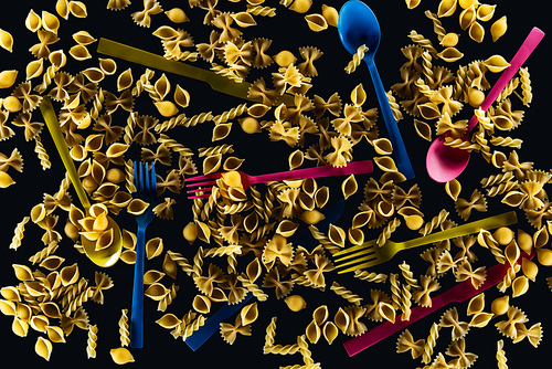 top view of mixed colorful cutlery with different kinds of pasta isolated on black