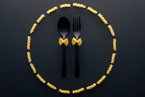 top view of farfalle pasta on spoon and fork in circle from rotini pasta