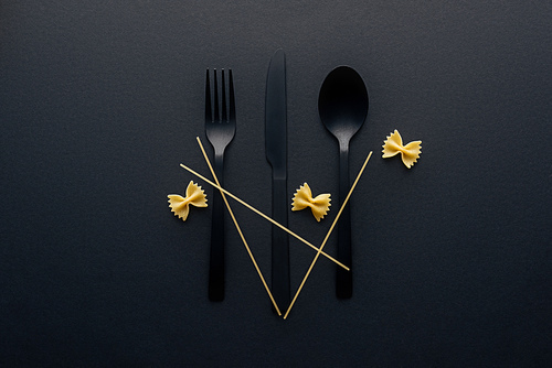 plastic cutlery with farfalle pasta and spaghetti on black background