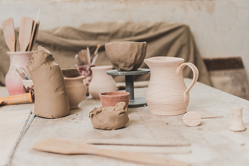 handmade pots, sculpted clay bowl and pottery equipment on wooden table