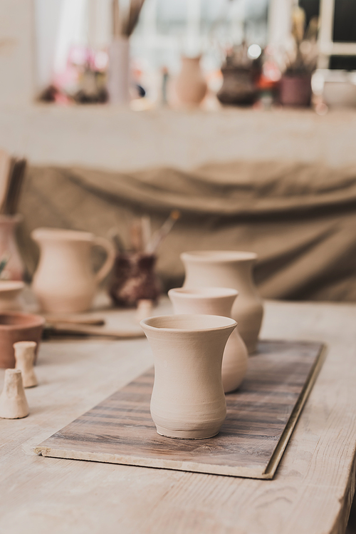handmade clay pots and pottery equipment on wooden table