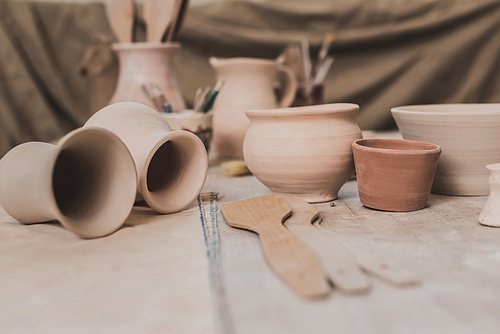 handmade clay pots and pottery equipment on wooden table in art studio