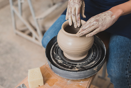 high angle view of young african american woman working with wet clay pot in pottery