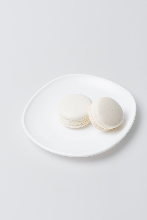 sweet macarons on plate isolated on white