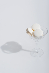 shadow near tasty macarons in dessert dish on white