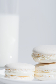 close up view of tasty macarons near blurred glass of milk isolated on white