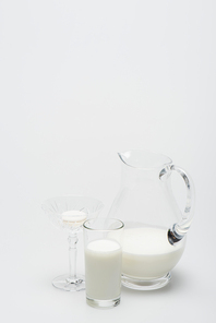 macaron in dessert dish near glass of milk and jug on white