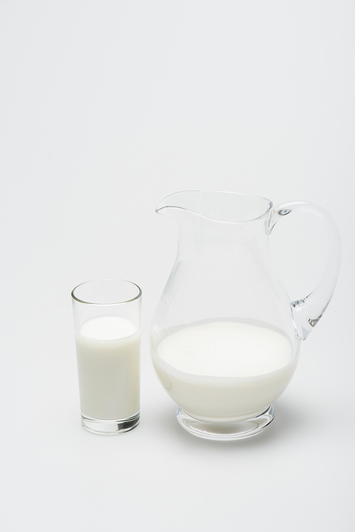 glass of milk and jug on white background