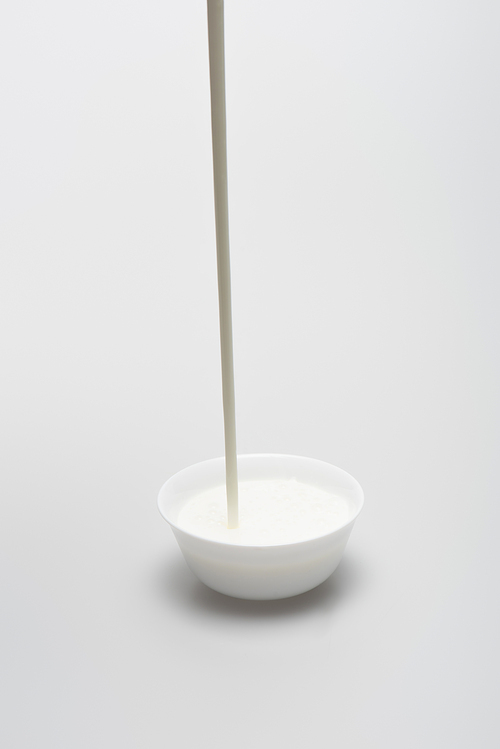 milk pouring in small bowl on white background