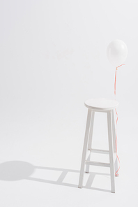 balloon near high wooden stool on white background
