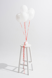 lightweight balloons above stool with ball of thread on white
