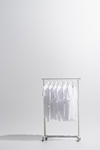 collection of stylish t-shirts hanging on clothes rack isolated on grey