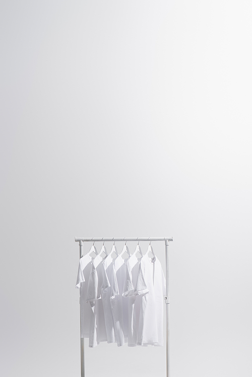 white t-shirts hanging on clothes rack isolated on grey