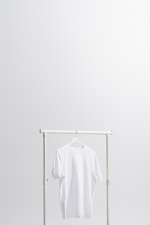white t-shirt hanging on clothes rack isolated on grey