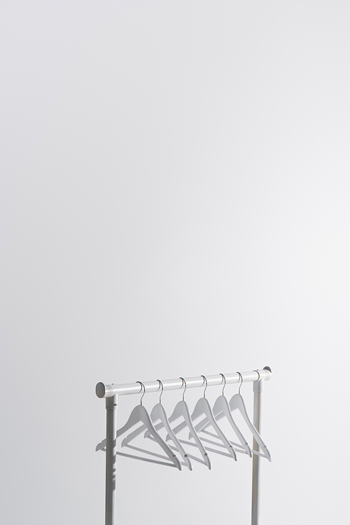 collection of white hangers on garment rack isolated on grey