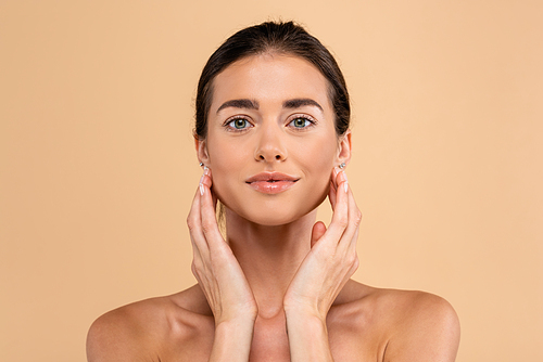 front view of young woman touching perfect face skin isolated on beige, beauty concept