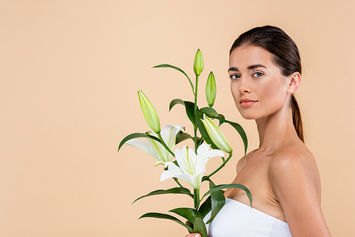 pretty woman  near white lily flowers isolated on beige, beauty concept