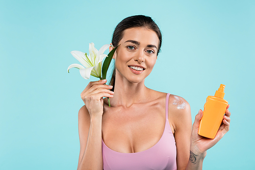 cheerful woman with sunblock and white lily  isolated on blue