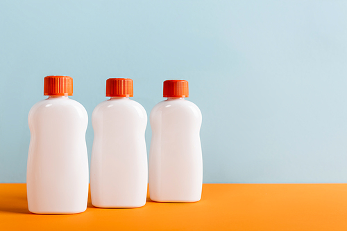white bottles of sunblock on orange surface isolated on blue