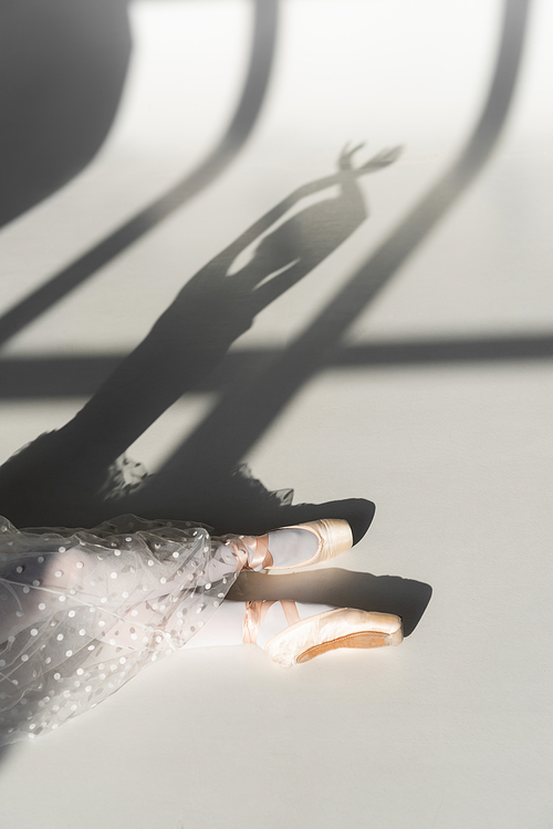 Cropped view of ballerina sitting on grey background