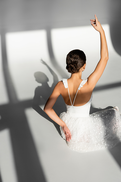 Back view of ballerina sitting on grey background